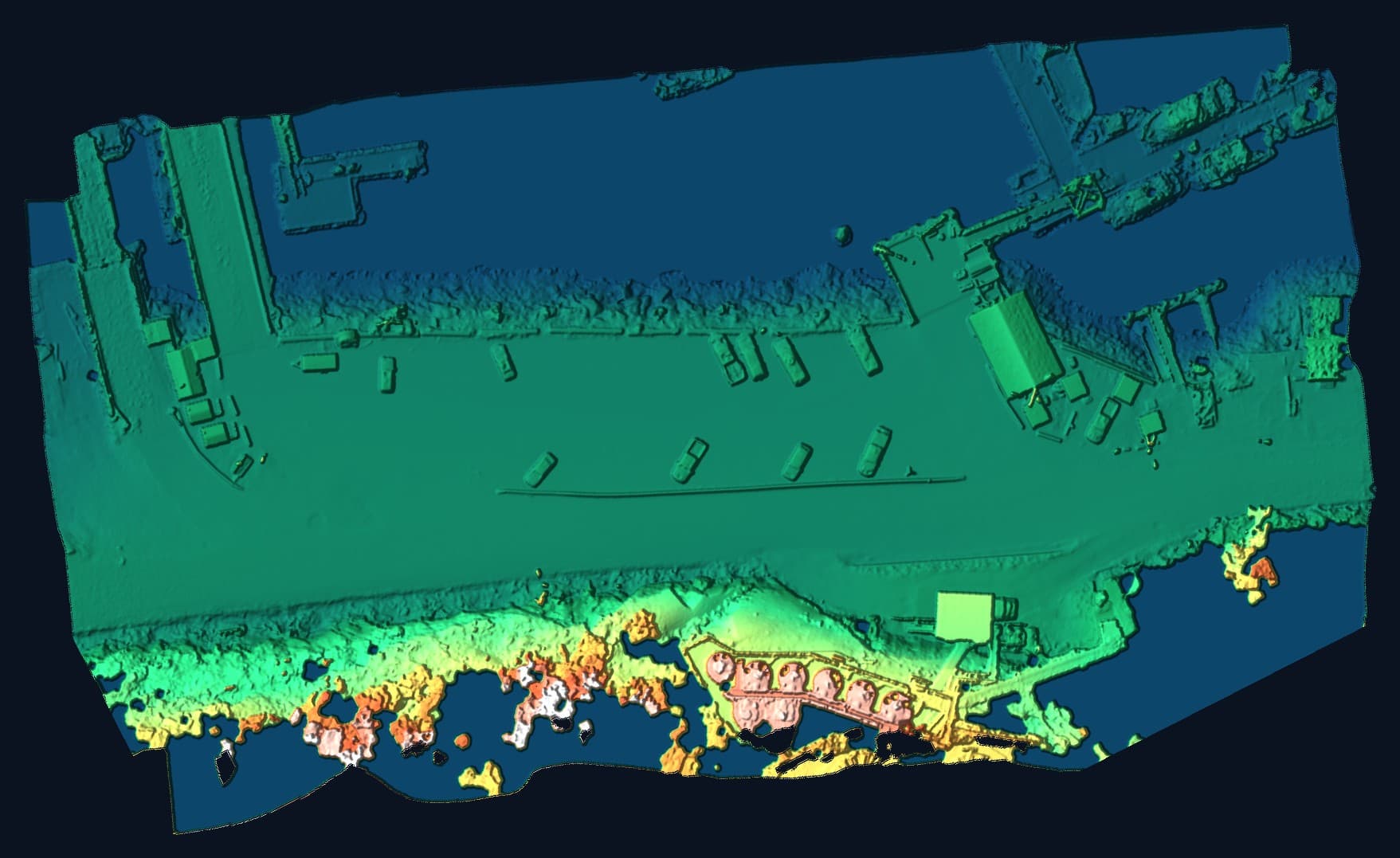 Drone LiDAR surface model of a working waterfront coloured by elevation: water in blue, lot and road in green, fuel tanks and bluff in orange and white